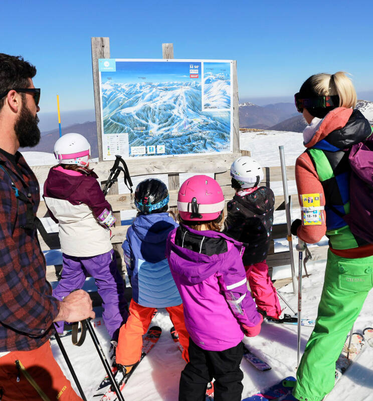 Les stations de ski Famille regardant le plan des pistes - Image colorée, bonheur partagé, bons moments au mourtis